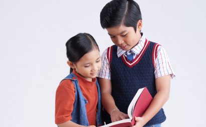 Look at this picture Vietnamese schoolboy showing interesting book to his classmate